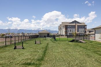 A park with a grassy field and a building in the background.